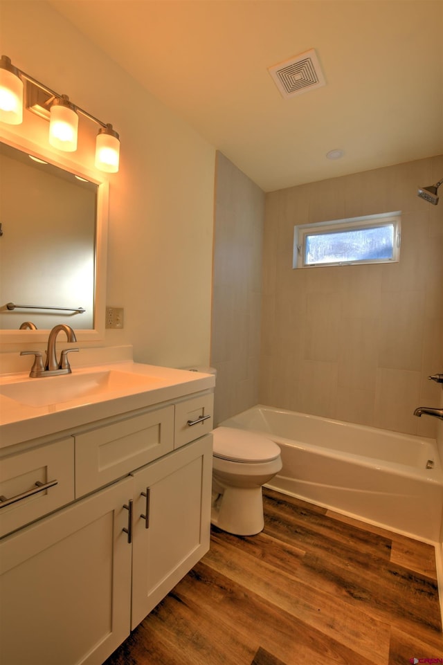 full bathroom with visible vents, bathing tub / shower combination, toilet, wood finished floors, and vanity