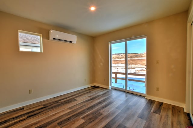 unfurnished room featuring dark wood-type flooring, a wall mounted air conditioner, and baseboards