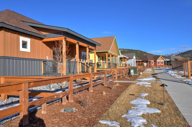 view of property exterior featuring a mountain view, roof with shingles, board and batten siding, and a residential view