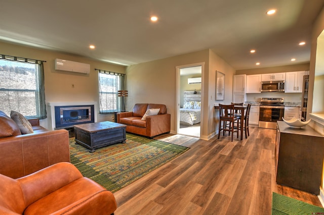 living room with recessed lighting, baseboards, an AC wall unit, and wood finished floors