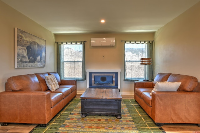 living area featuring a wall unit AC, wood finished floors, and baseboards