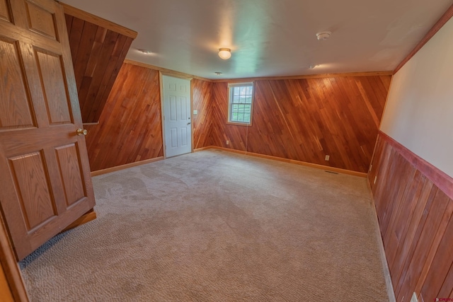 carpeted empty room featuring wooden walls and crown molding