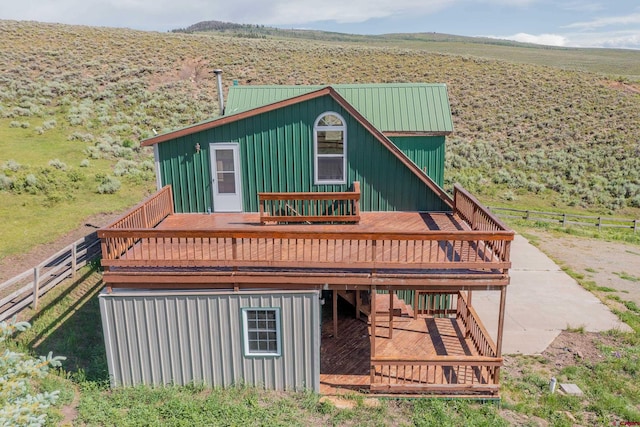 back of house with a wooden deck, an outdoor structure, and a rural view