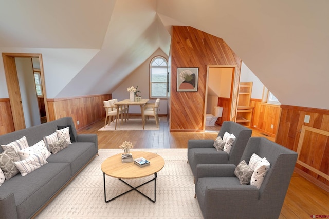 living room featuring lofted ceiling, wood walls, and light wood-type flooring