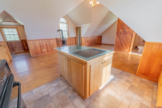 kitchen with black electric stovetop, wood walls, range, and light tile floors