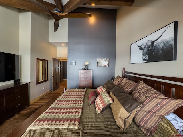 bedroom featuring dark wood-type flooring, a towering ceiling, ceiling fan, and beam ceiling