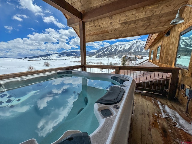 snow covered deck featuring a mountain view and a hot tub