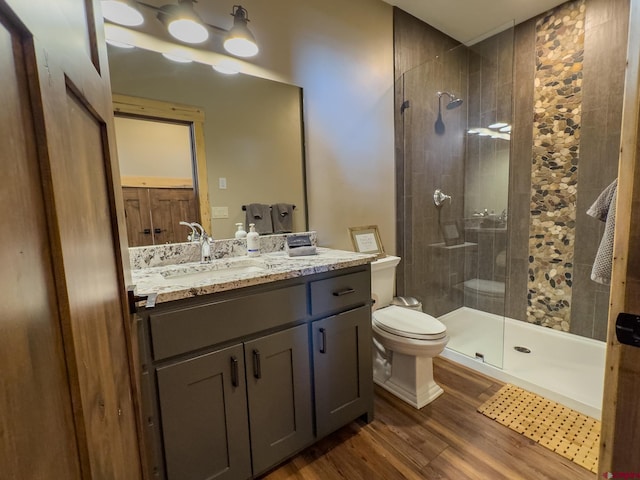 bathroom with walk in shower, wood-type flooring, oversized vanity, and toilet