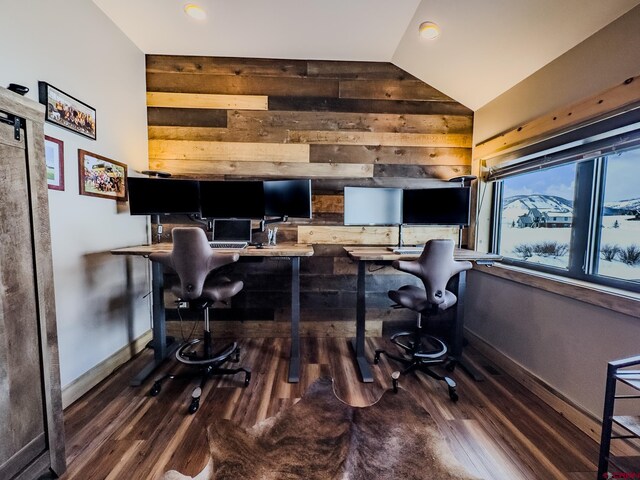 office area with vaulted ceiling, dark hardwood / wood-style flooring, a barn door, and wood walls