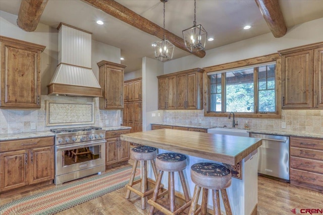 kitchen with light hardwood / wood-style floors, stainless steel appliances, custom exhaust hood, a center island, and sink