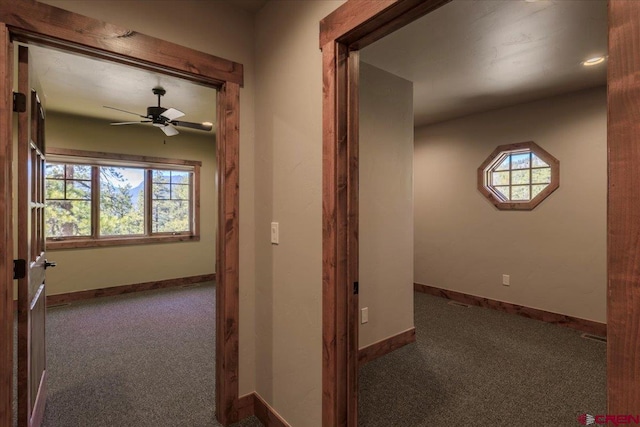 corridor with plenty of natural light and dark colored carpet