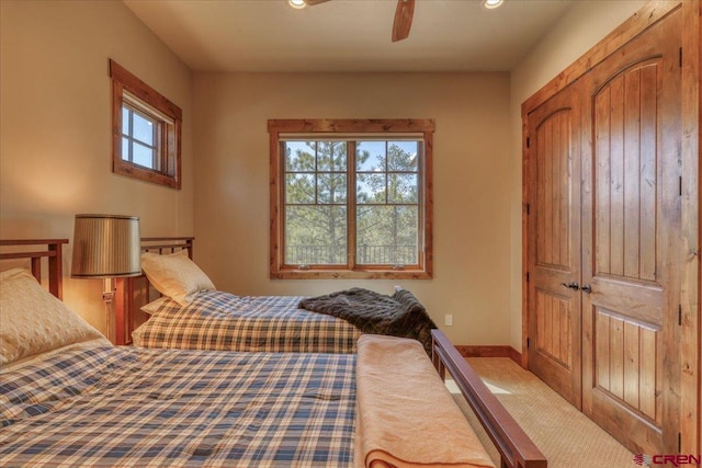 carpeted bedroom featuring ceiling fan and a closet