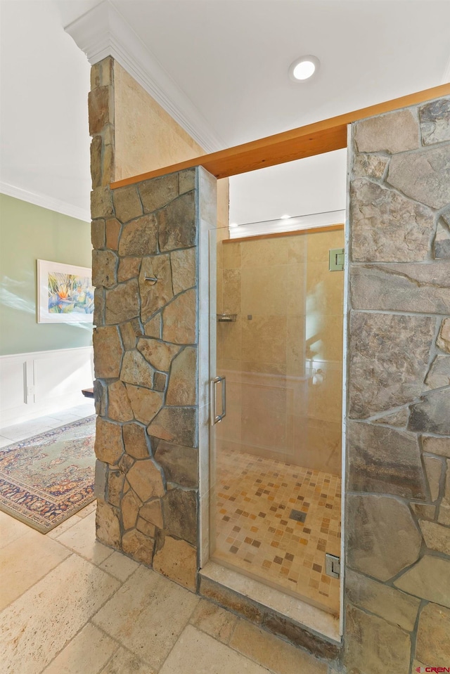 bathroom with a shower with shower door, tile flooring, and ornamental molding