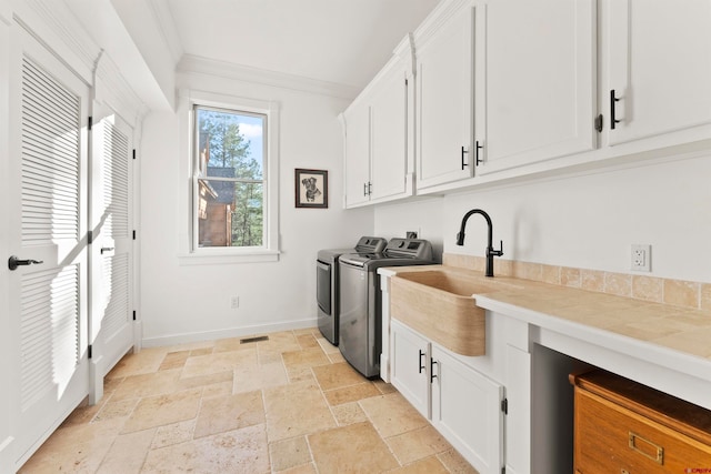 laundry room featuring crown molding, light tile flooring, washing machine and dryer, sink, and cabinets