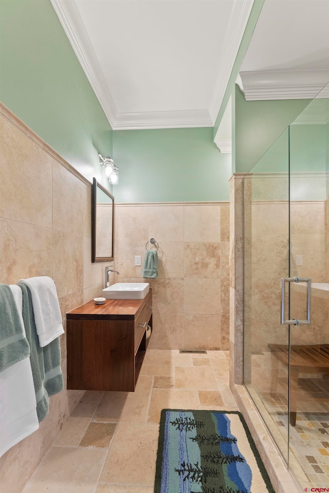 bathroom featuring ornamental molding, tile floors, a shower with shower door, tile walls, and vanity