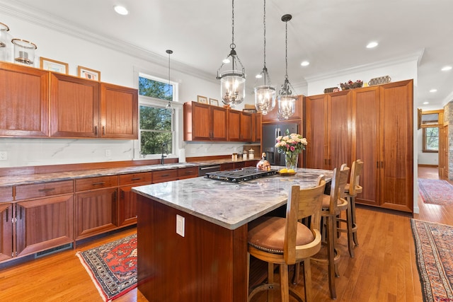 kitchen featuring a center island, ornamental molding, light hardwood / wood-style flooring, stainless steel appliances, and pendant lighting