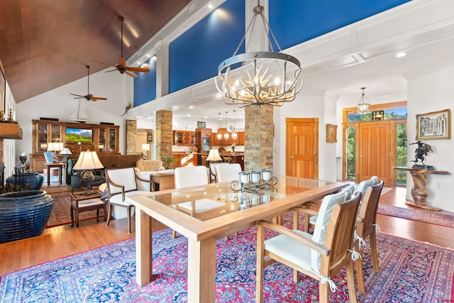 dining area with ceiling fan with notable chandelier, a towering ceiling, hardwood / wood-style flooring, and ornamental molding