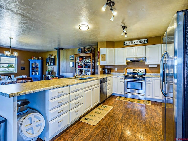 kitchen featuring appliances with stainless steel finishes, sink, a wood stove, a kitchen breakfast bar, and kitchen peninsula