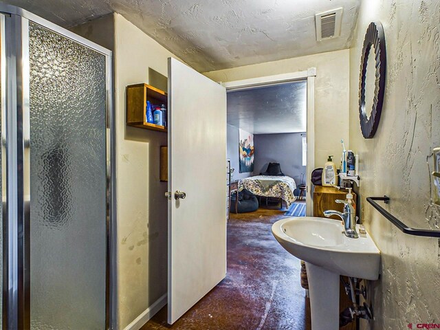 bathroom with a shower with shower door and concrete floors