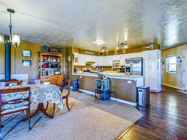 kitchen with stainless steel refrigerator with ice dispenser, a breakfast bar area, dark hardwood / wood-style floors, pendant lighting, and white cabinets