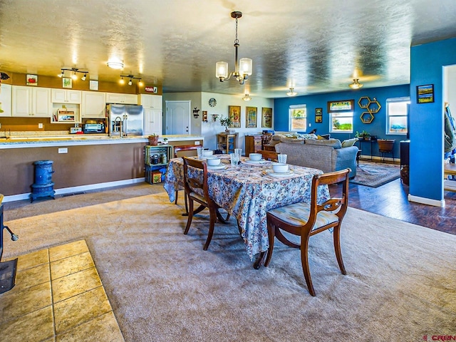 carpeted dining room featuring a textured ceiling and ceiling fan with notable chandelier