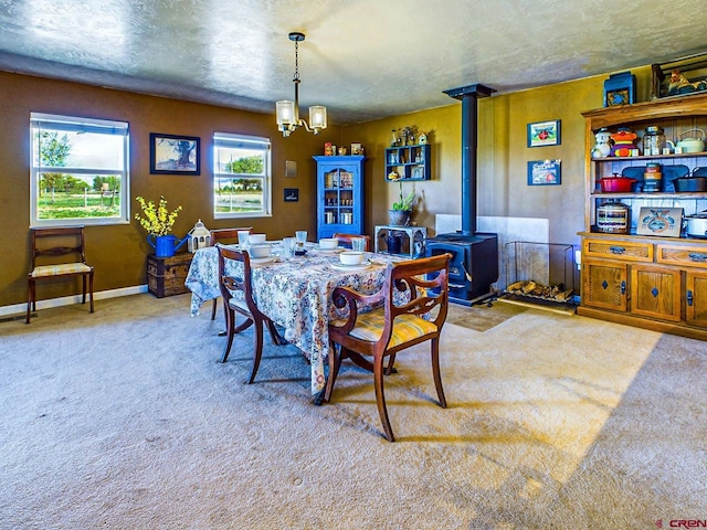 dining space with light colored carpet, an inviting chandelier, a wood stove, and a textured ceiling