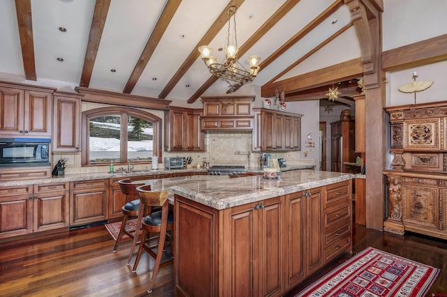 kitchen featuring black microwave, a center island, hanging light fixtures, tasteful backsplash, and a notable chandelier