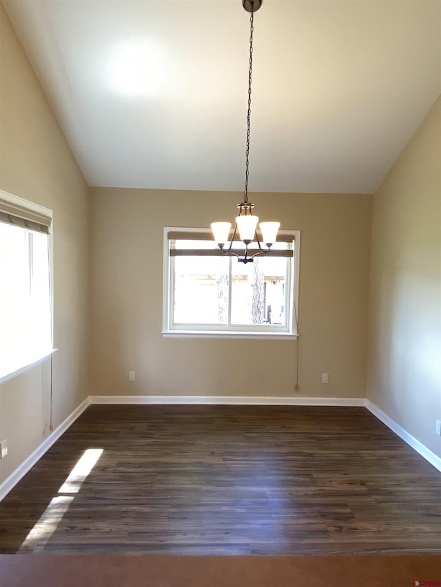 empty room featuring a notable chandelier, dark hardwood / wood-style floors, and vaulted ceiling