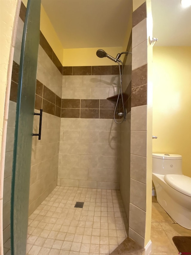 bathroom with a tile shower and toilet