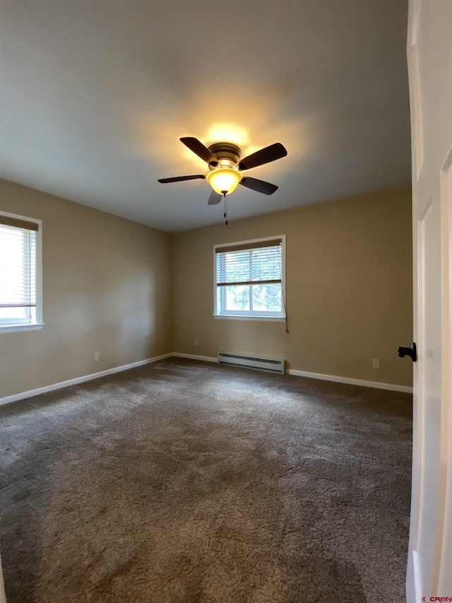 unfurnished room with dark colored carpet, ceiling fan, a healthy amount of sunlight, and a baseboard heating unit