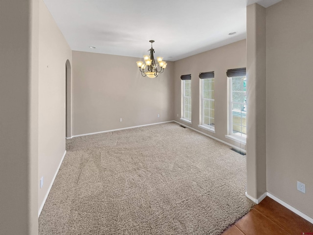 carpeted empty room with a notable chandelier