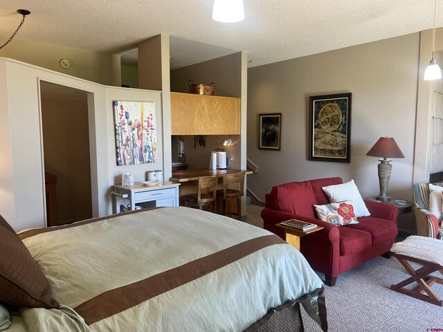 bedroom featuring a textured ceiling, carpet flooring, and lofted ceiling