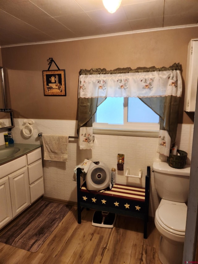 bathroom featuring crown molding, hardwood / wood-style floors, tile walls, toilet, and vanity