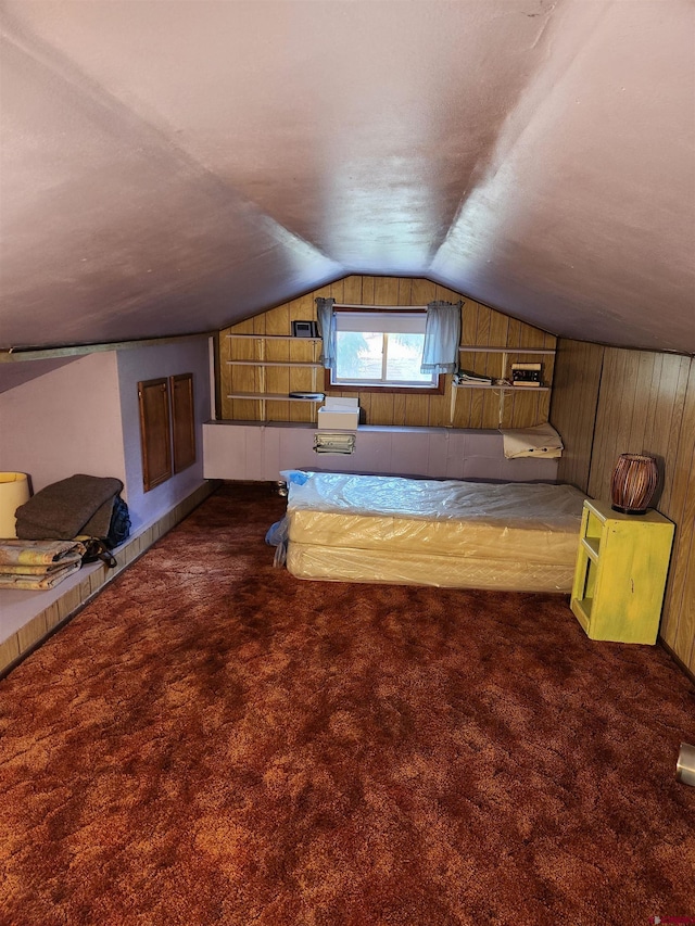 bonus room featuring wooden walls, lofted ceiling, and dark colored carpet