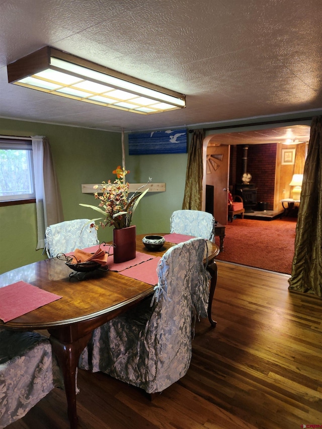 dining space with a textured ceiling, hardwood / wood-style floors, and a wood stove