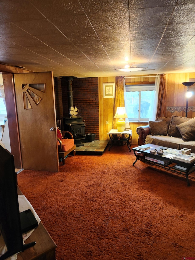 living room featuring wood walls, brick wall, carpet, and a wood stove