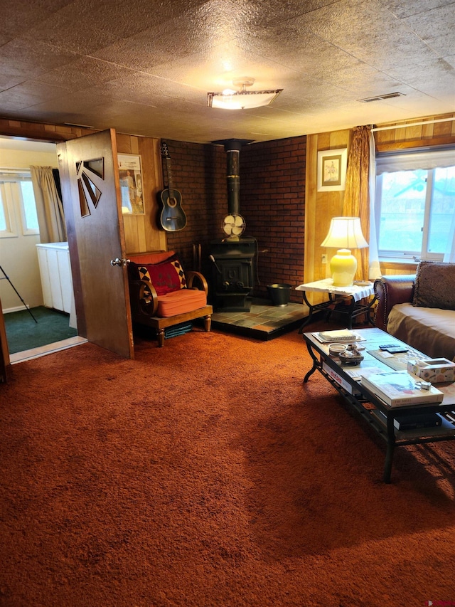 living room with carpet flooring, wood walls, brick wall, and a wood stove