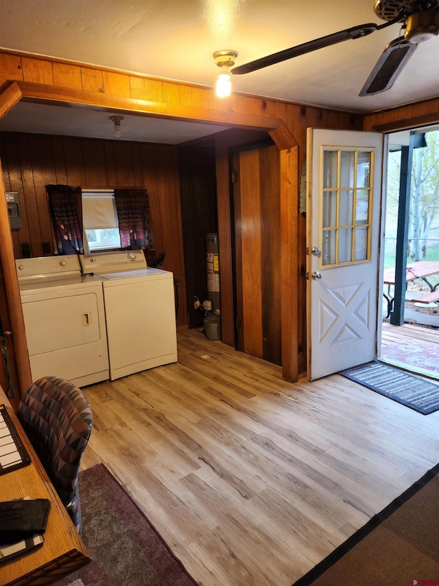 interior space with ceiling fan, wooden walls, light hardwood / wood-style floors, and washing machine and dryer