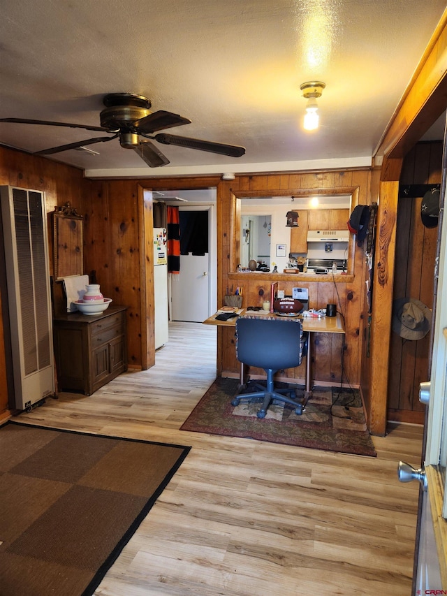 home office featuring ceiling fan, wood walls, and light wood-type flooring