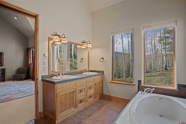 bathroom featuring a tub, vanity, a healthy amount of sunlight, and vaulted ceiling