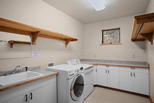 clothes washing area with separate washer and dryer, sink, and cabinets