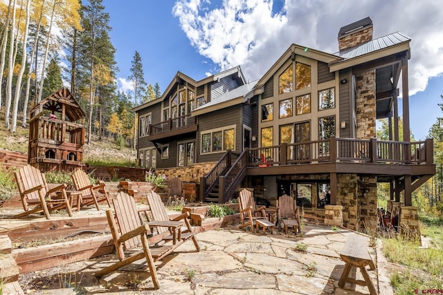 back of property featuring a wooden deck and a patio