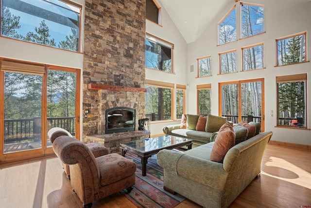 living room with a fireplace, a towering ceiling, and light wood-type flooring