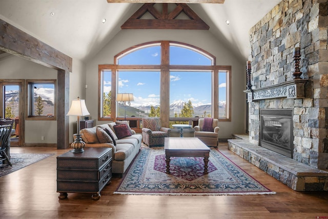 living room featuring a mountain view, wood-type flooring, high vaulted ceiling, beamed ceiling, and a fireplace