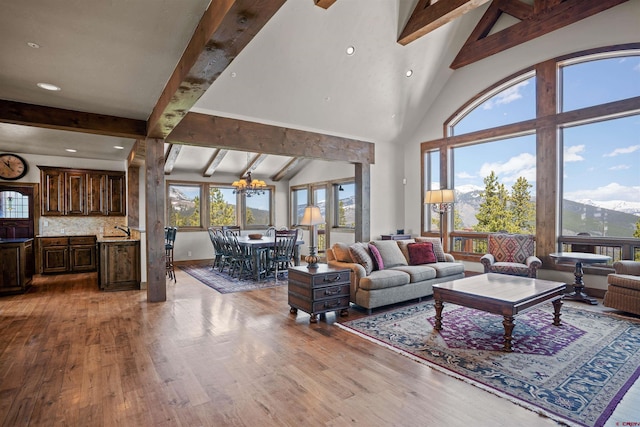 living room featuring a notable chandelier, beam ceiling, high vaulted ceiling, and light hardwood / wood-style flooring