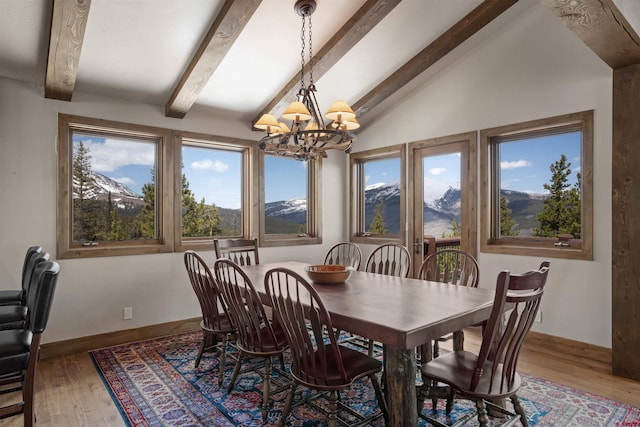 dining area with a mountain view, lofted ceiling with beams, hardwood / wood-style flooring, and an inviting chandelier