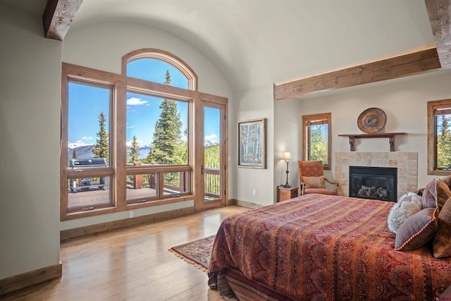 bedroom featuring a tiled fireplace, multiple windows, and light wood-type flooring