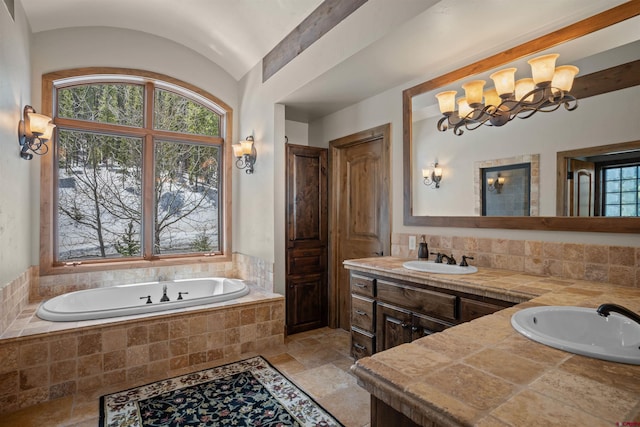 bathroom featuring tiled bath, vanity, lofted ceiling, and a notable chandelier