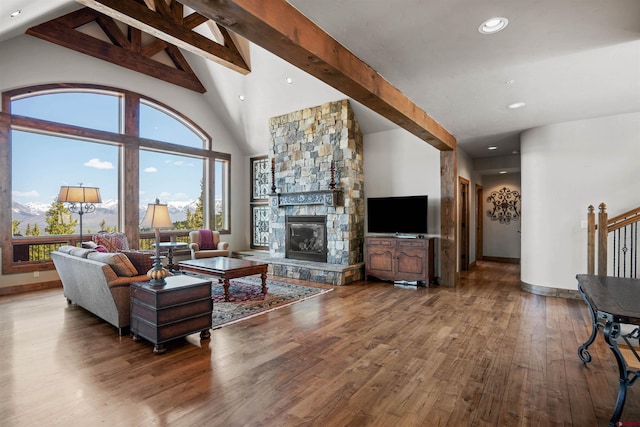 living room with beamed ceiling, a stone fireplace, hardwood / wood-style floors, and high vaulted ceiling