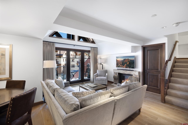 living room featuring a fireplace, light hardwood / wood-style flooring, and french doors